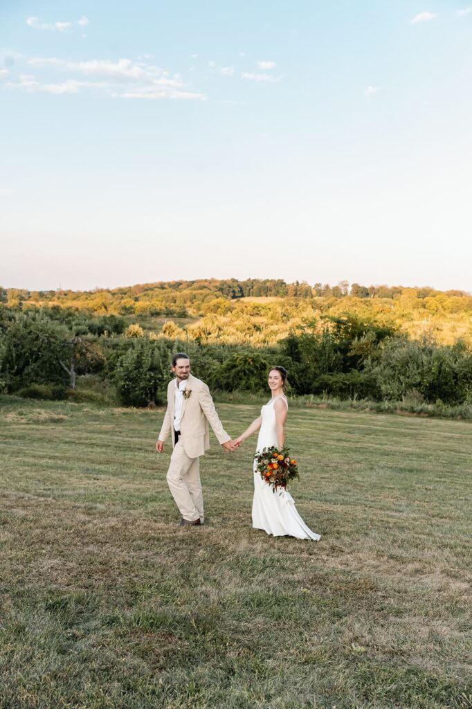 Bride and groom walking through the grounds of The Homestead Farm wedding venue