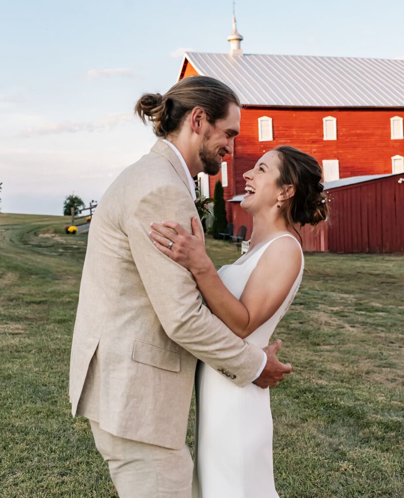 Bride and groom embracing near the red barn at The Homestead Farm Historic Wright-Barton Venue